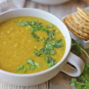 Vegan red lentil soup in bowl, garnished with cilantro.