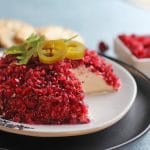 Cream cheese topped with cranberry salsa on plate.