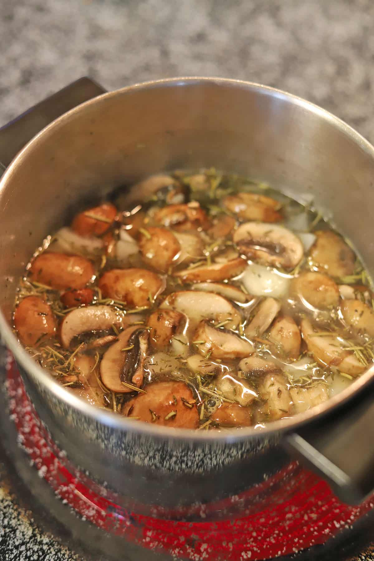 Mushrooms with herbs in soup pot.
