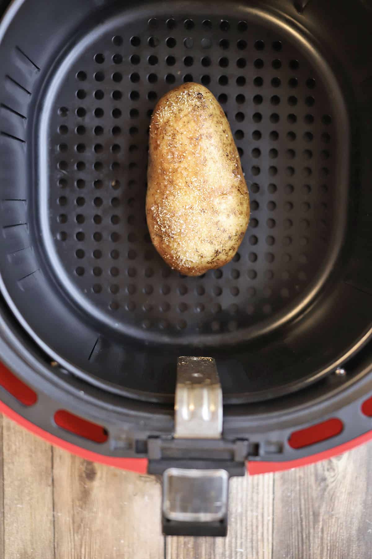 Russet potato in air fryer basket.