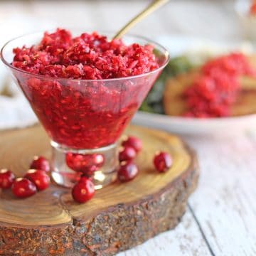 Cranberry salsa in cocktail glass by whole cranberries.