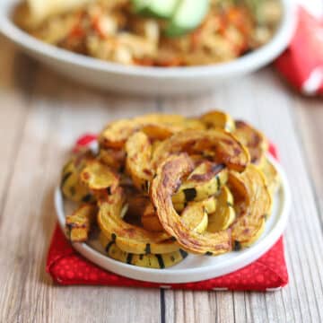 Roasted delicata squash with rosemary on small round plate.