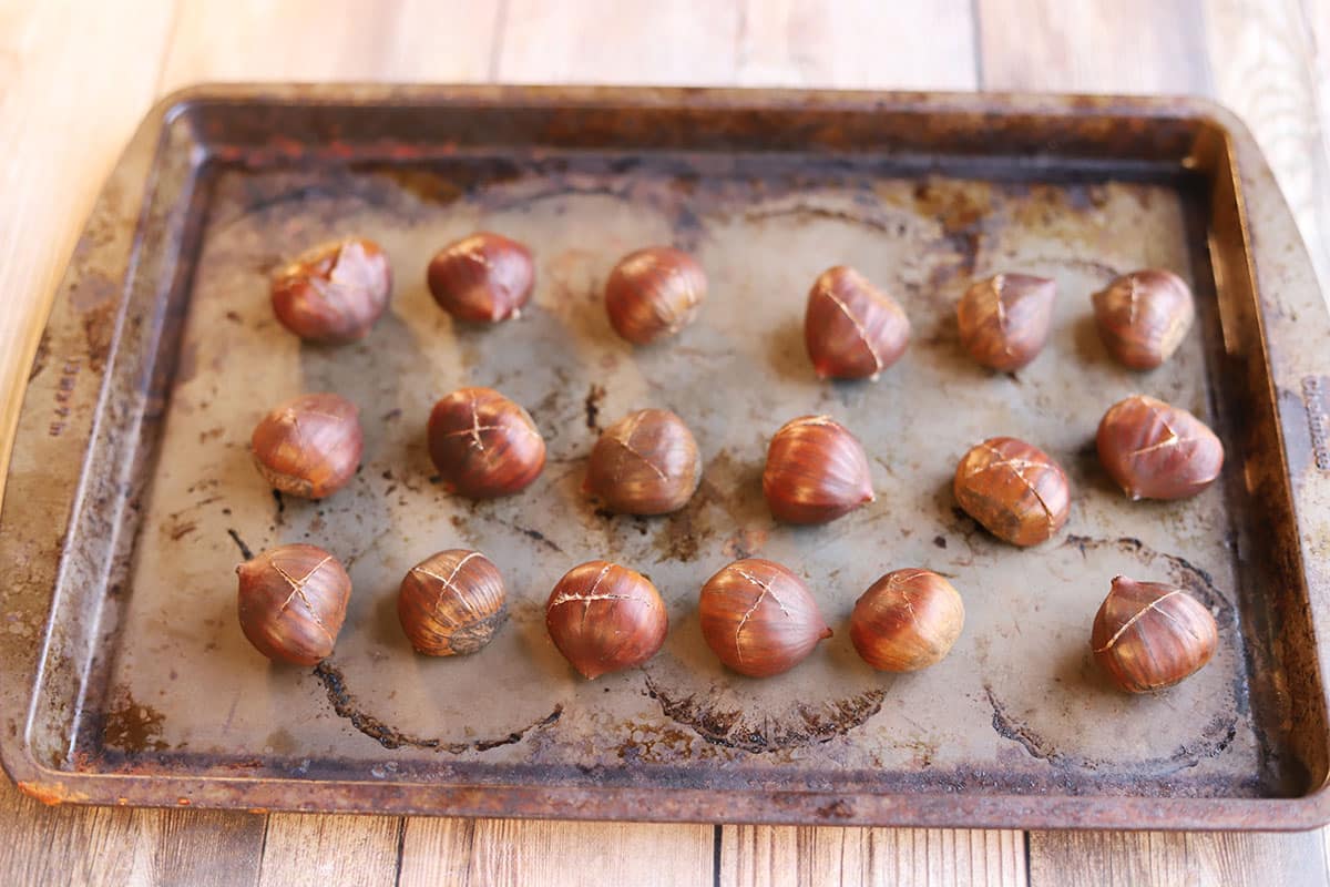 Scored chestnuts on a baking sheet.