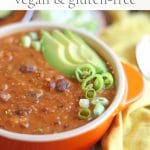 Text overlay: Three bean chili. Vegan and gluten-free. Bowl of chili with avocado, onions, and peppers.