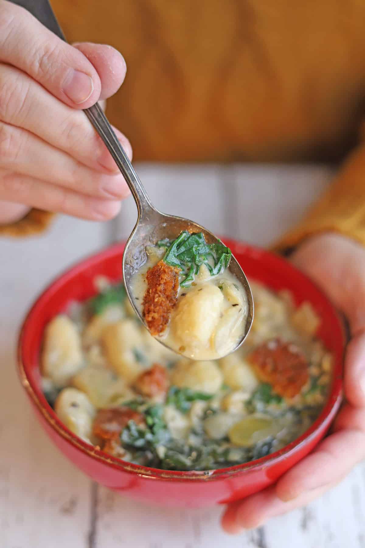 Spoon holding vegan gnocchi soup.