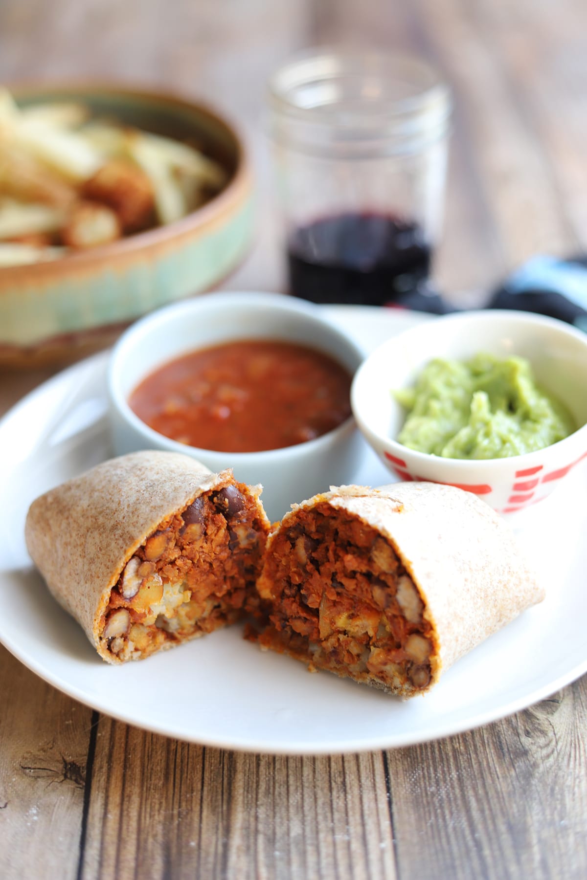 Soyrizo and tater tot burrito on plate with guacamole and salsa.