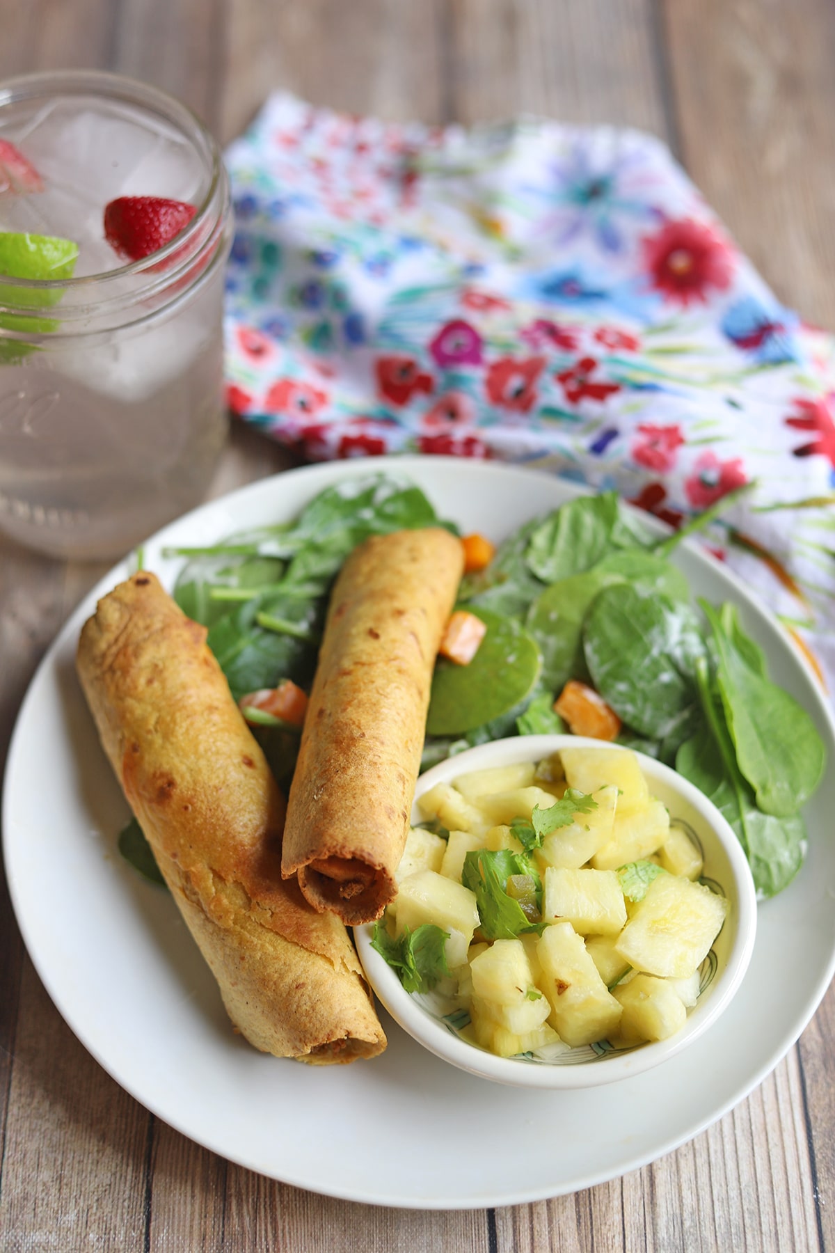 Jackfruit taquitos on plate with spinach salad and pineapple salsa.