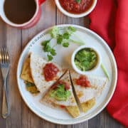 Vegan breakfast quesadilla with eggy tofu on plate with guacamole and cilantro.