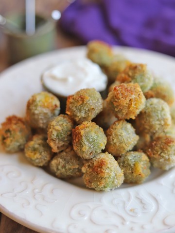 Fried stuffed olives on plate with dipping sauce.