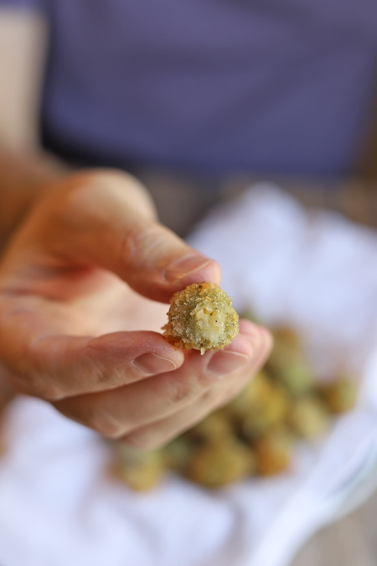 Hand holding fried olive.