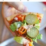 Text overlay: Cheeseburger pizza. Quick & easy vegan dinner. Hand holding slice of pizza.