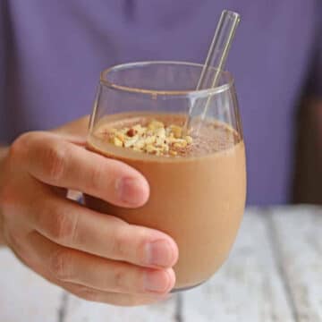 Hand holding a chocolate peanut butter smoothie.