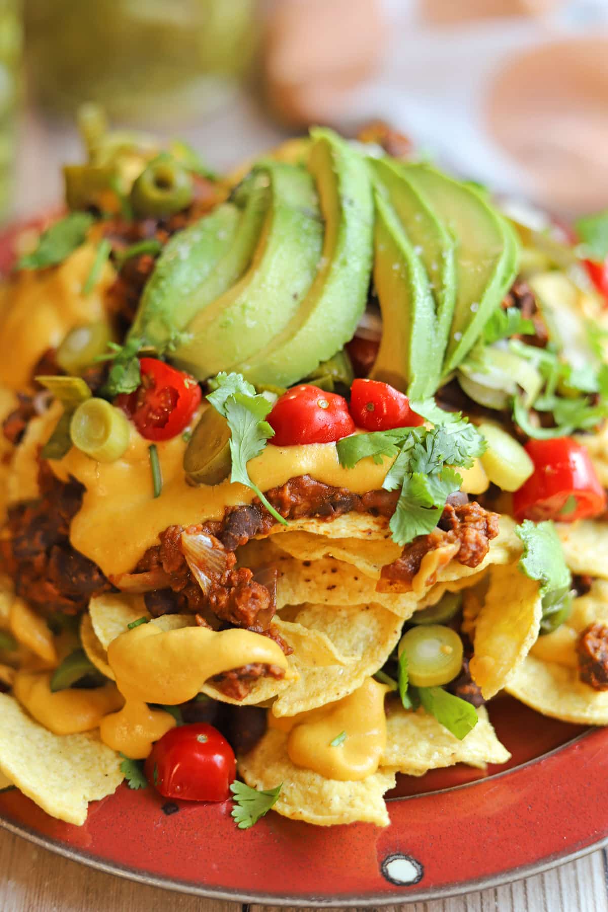 Close-up loaded vegan nachos with black beans, soy chorizo, tomatoes, and jalapenos.