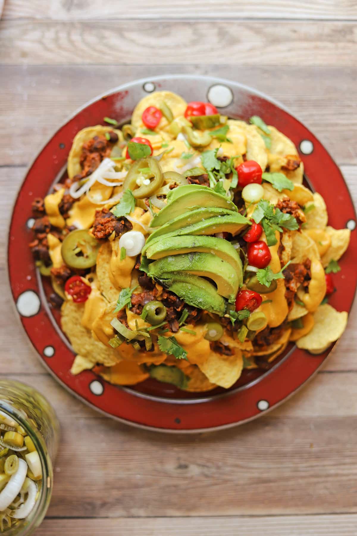 Overhead platter of vegan nachos with sliced avocado on top.