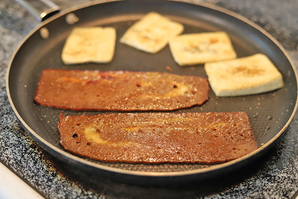 Seitan bacon and tofu slabs on skillet.