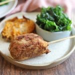 Vegan fried chicken drumstick on plate with sweet potato and kale.