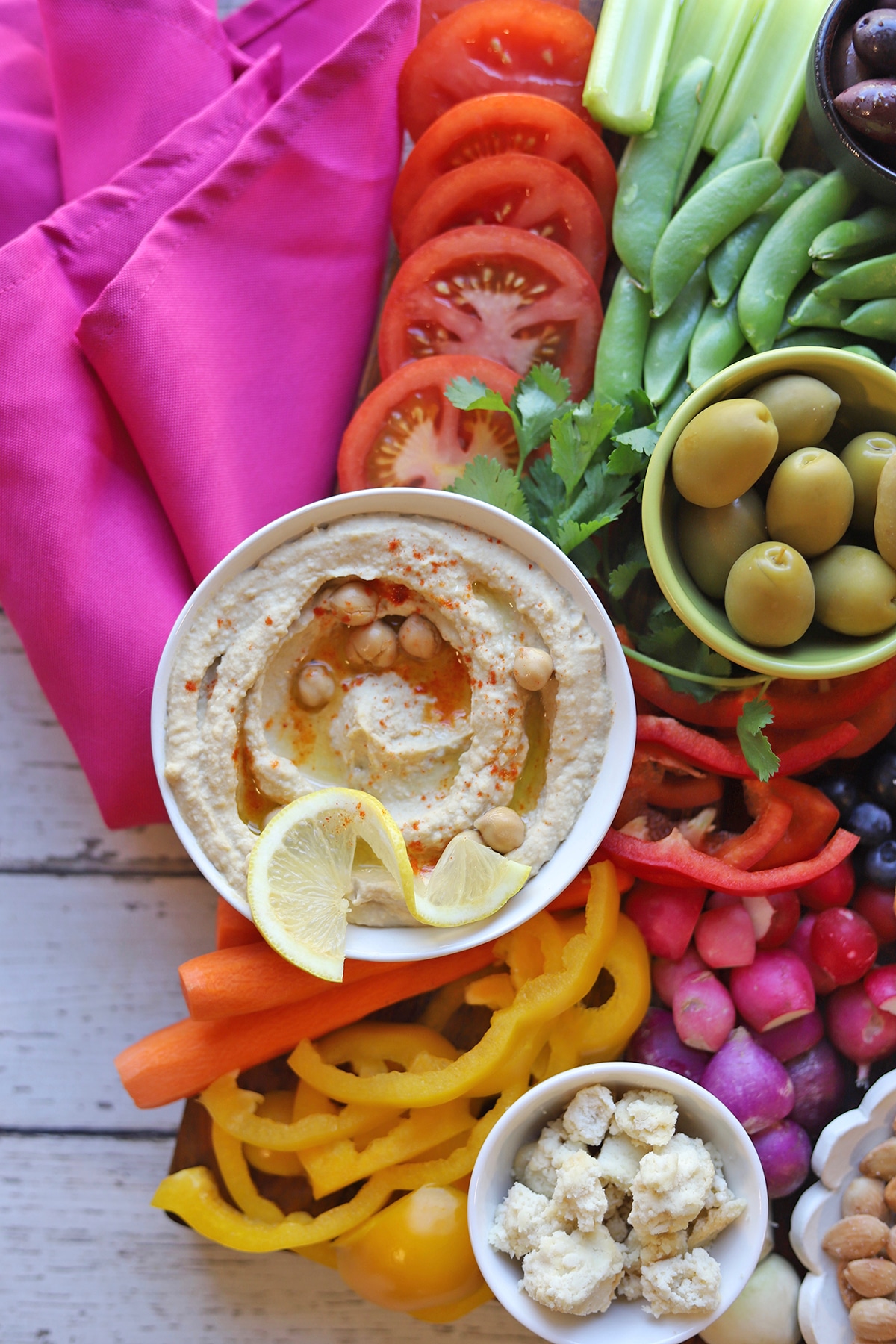 Close-up hummus garnished with chickpeas and oil on veggie tray.
