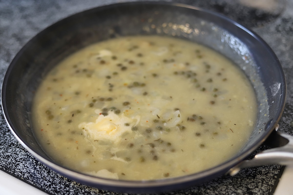 Lemon and white wine sauce on stove with vegan butter melting in it.