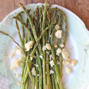 Asparagus on plate, topped with vegan feta cheese.