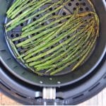 Text overlay: Air fryer asparagus. Easy vegan and gluten-free side dish. Stalks of cooked asparagus in air fryer basket.