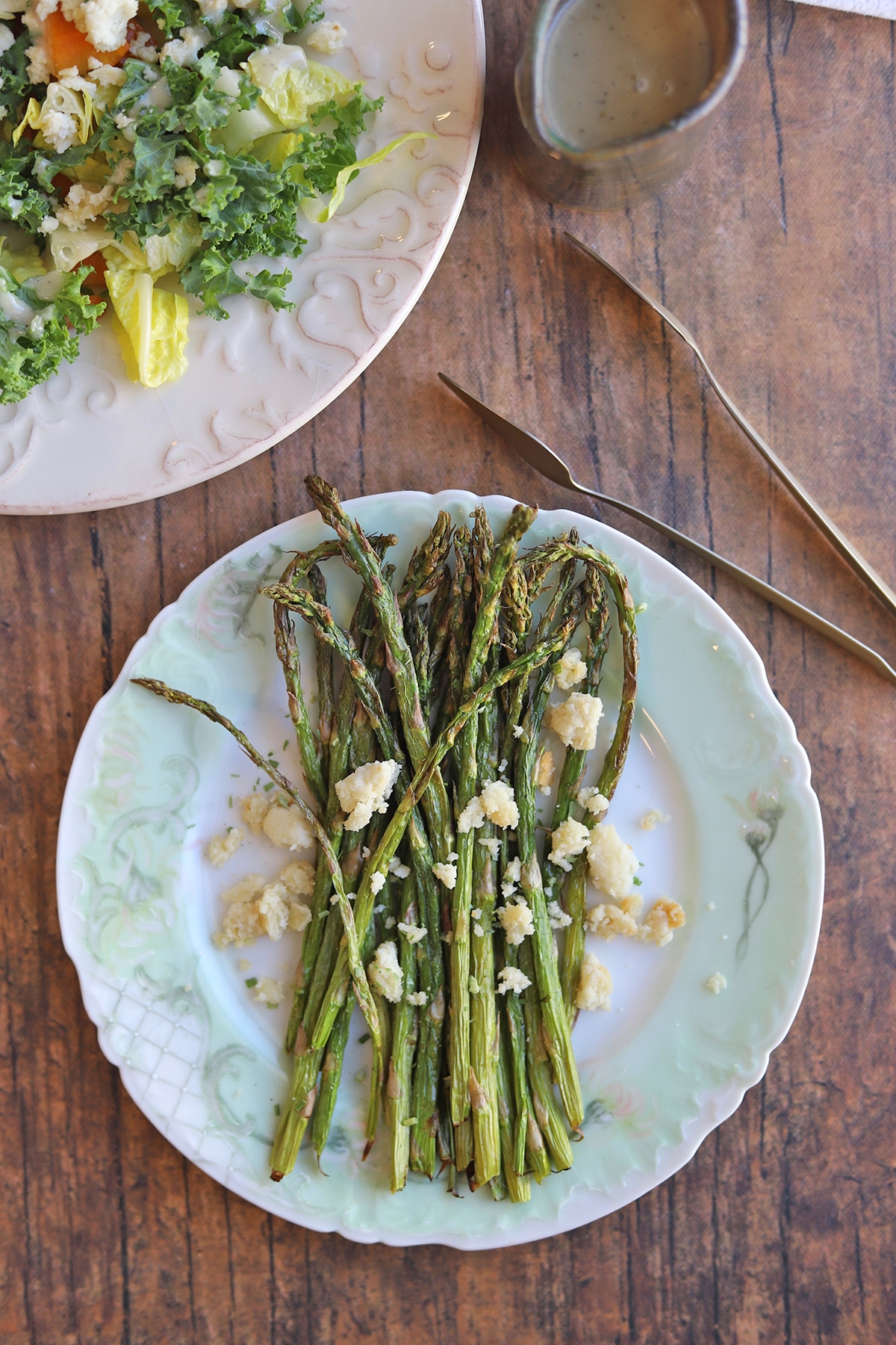 Air fried asparagus on plate by kale salad.