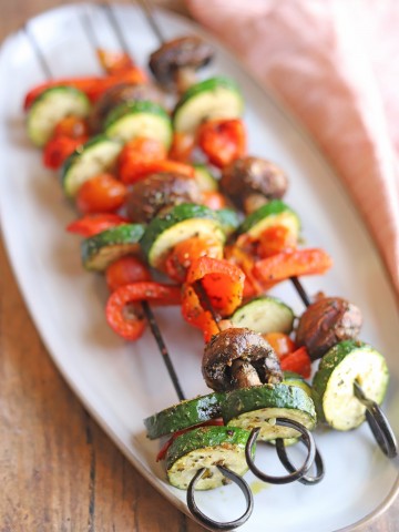 Zucchini, bell peppers, mushrooms, and tomatoes grilled on skewers.