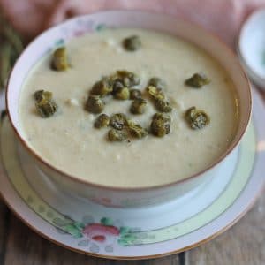 Roasted cauliflower soup in bowl, topped with fried capers.