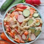 Text overlay: Vegan pasta salad. Fusilli noodle salad in bowl with sliced vegetables.