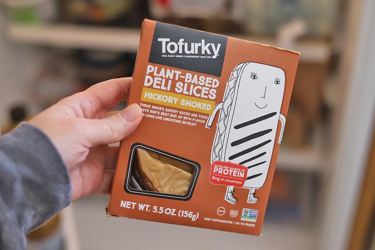 Hand holding Tofurky plant-based deli slices.