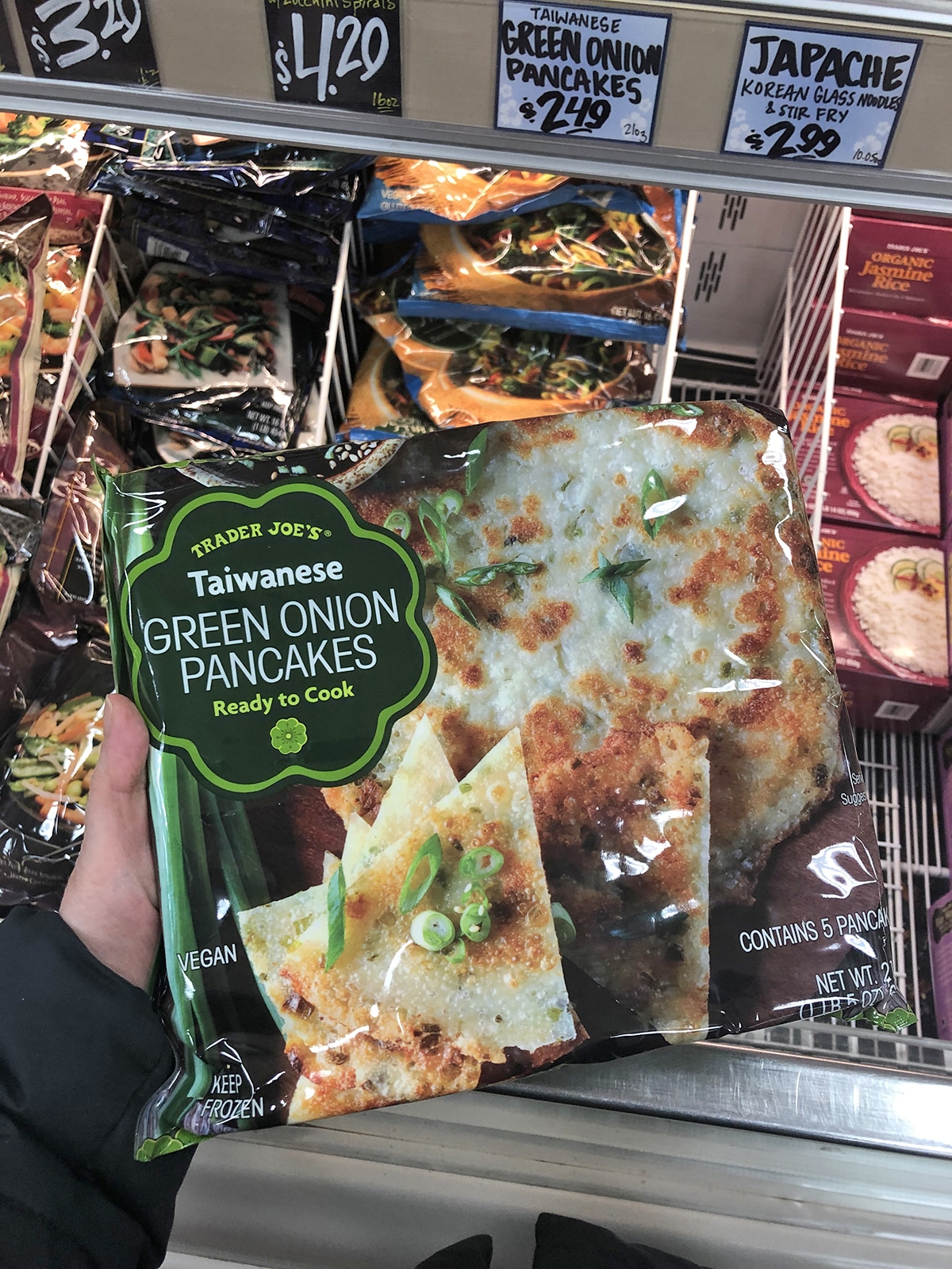 Hand holding package of green onion pancakes at Trader Joe's.
