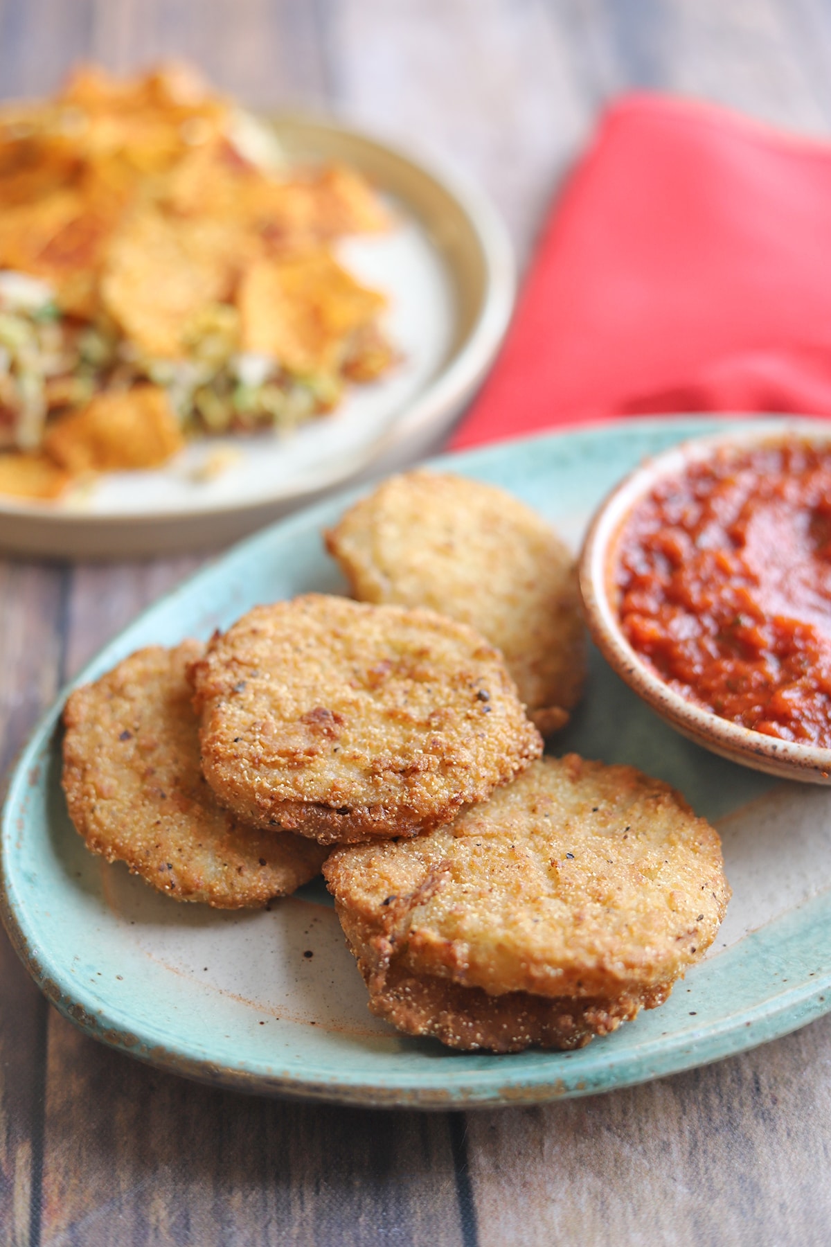Fried green tomatoes with red sauce on platter.