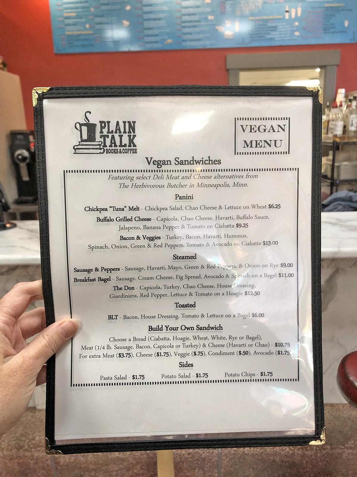 Hand holding vegan menu at Plain Talk Books and Coffee.