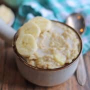 Vegan peanut butter banana oatmeal in white pot by silver spoon.
