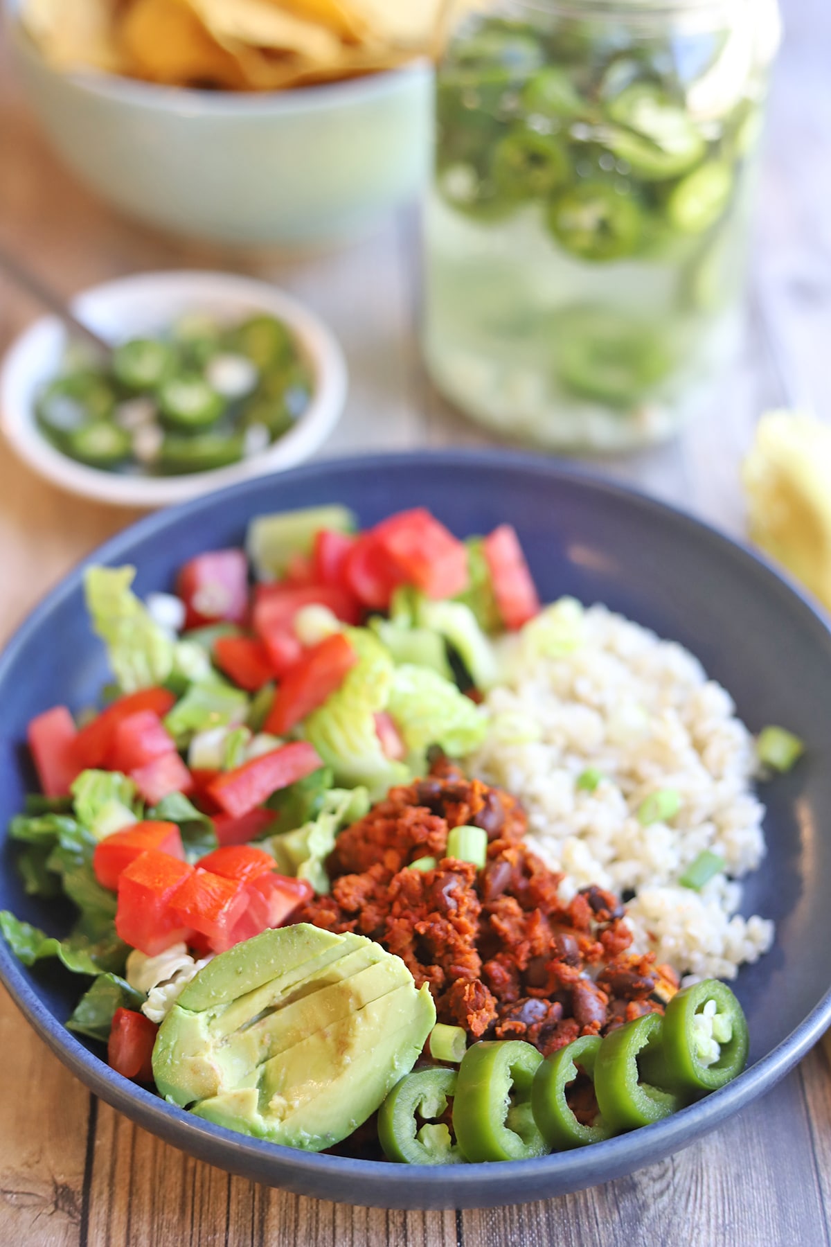 Burrito bowl with salad, rice, avocado, and pickled jalapenos.