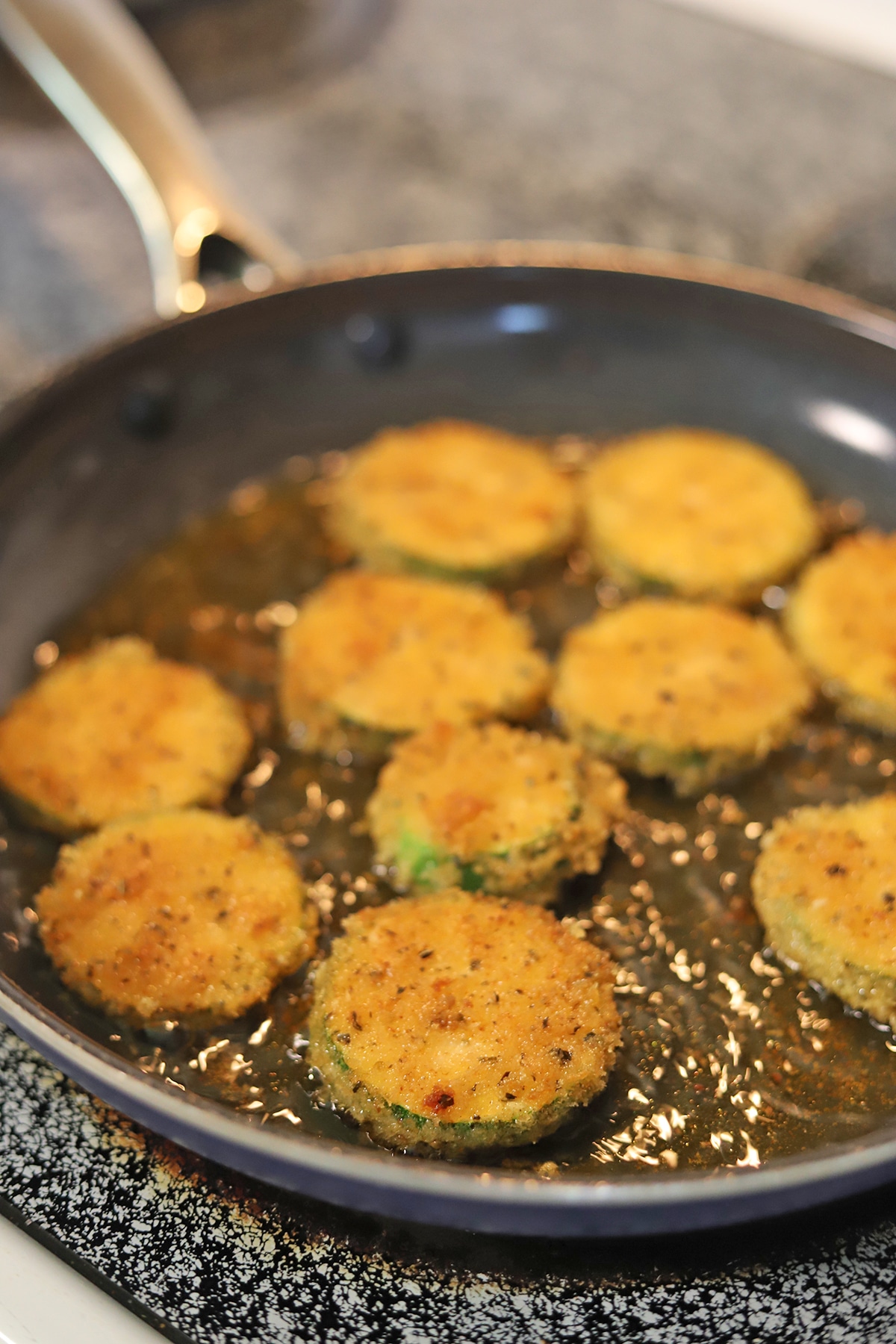 Zucchini slices frying in skillet.