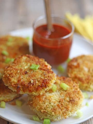 Vegan crab cakes on platter by cocktail sauce.