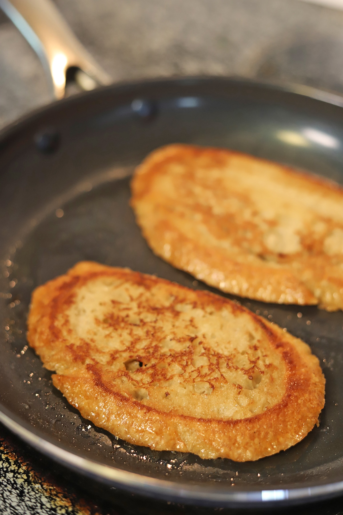 Two slices of French toast browning in skillet.