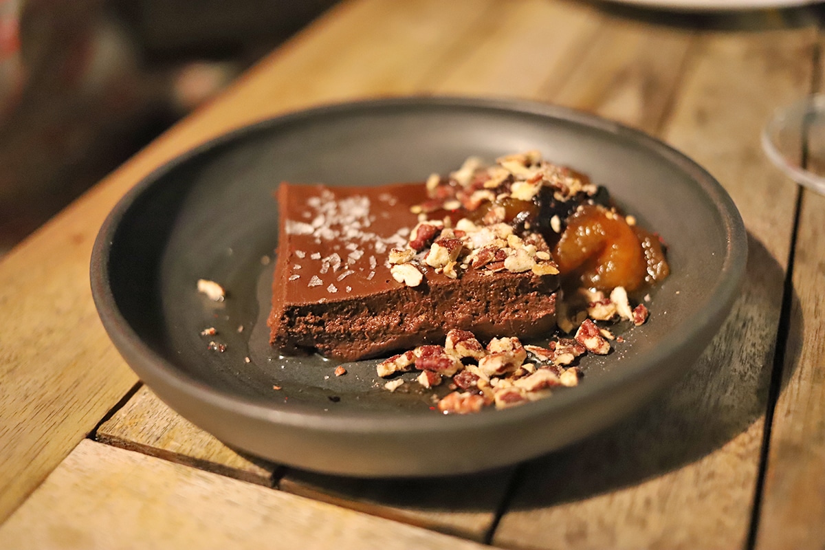 Square of chocolate dessert with stone fruit.