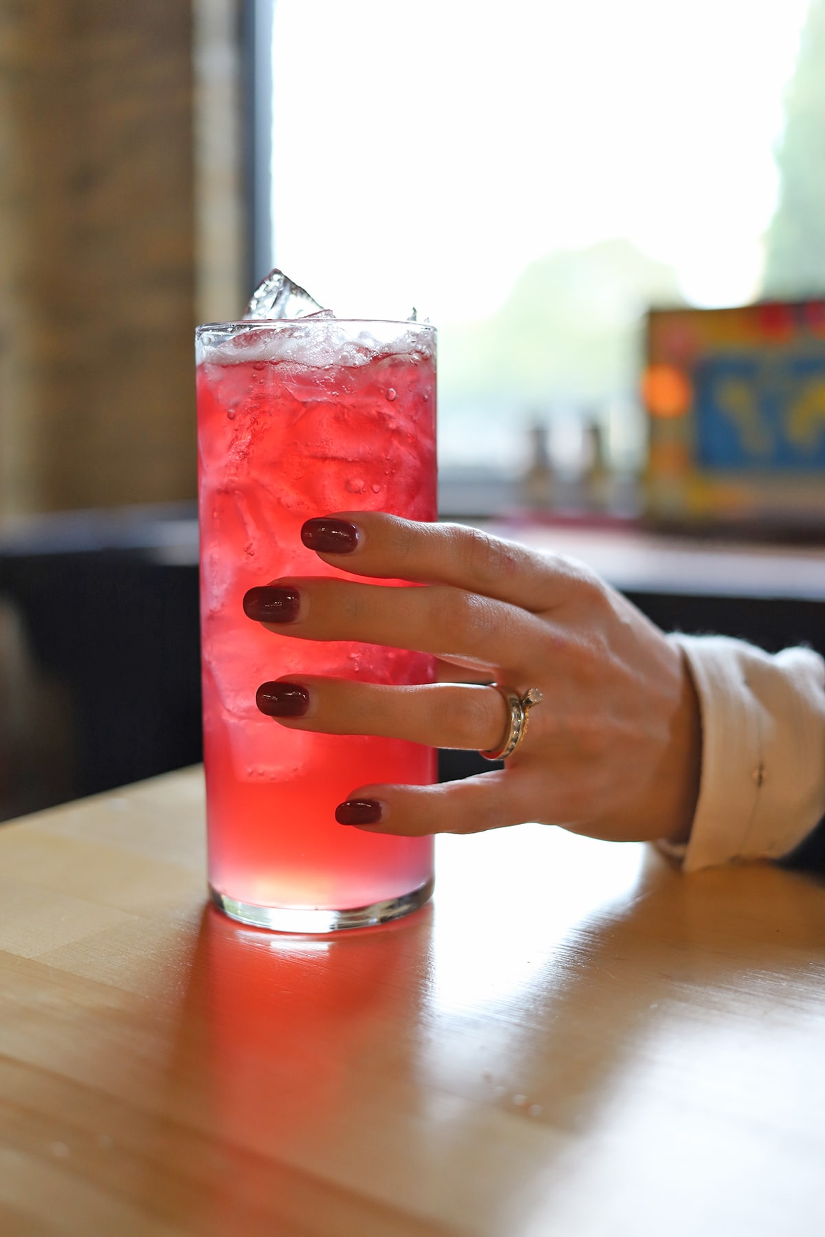 Hand holding glass of hibiscus cocktail.