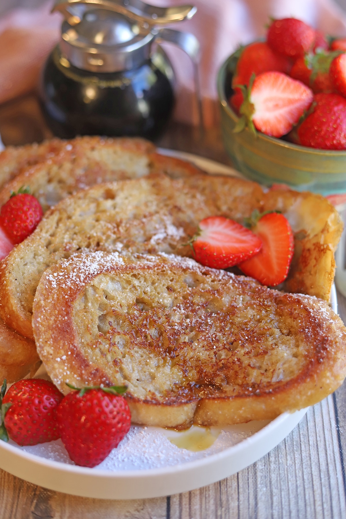 Platter of French toast with strawberries on table.