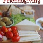 Text overlay: Vegan ideas for Friendsgiving. Cheeseboard on table.