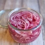 Glass jar with sliced onions in brine.