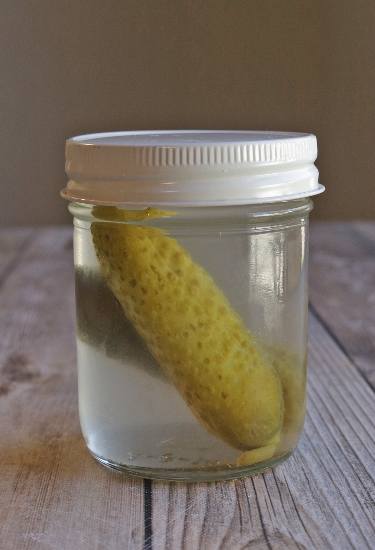 Two full sized pickles in jar with vodka and brine.