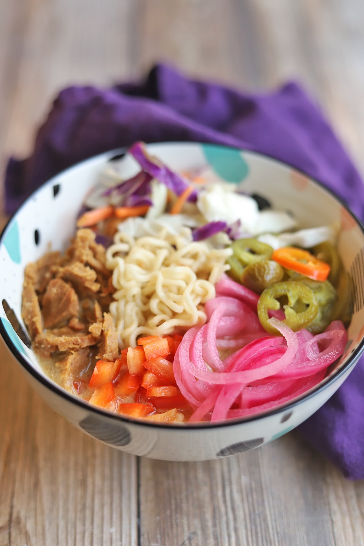 Bowl of ramen with pickled onions, jalapenos, cabbage and seitan.