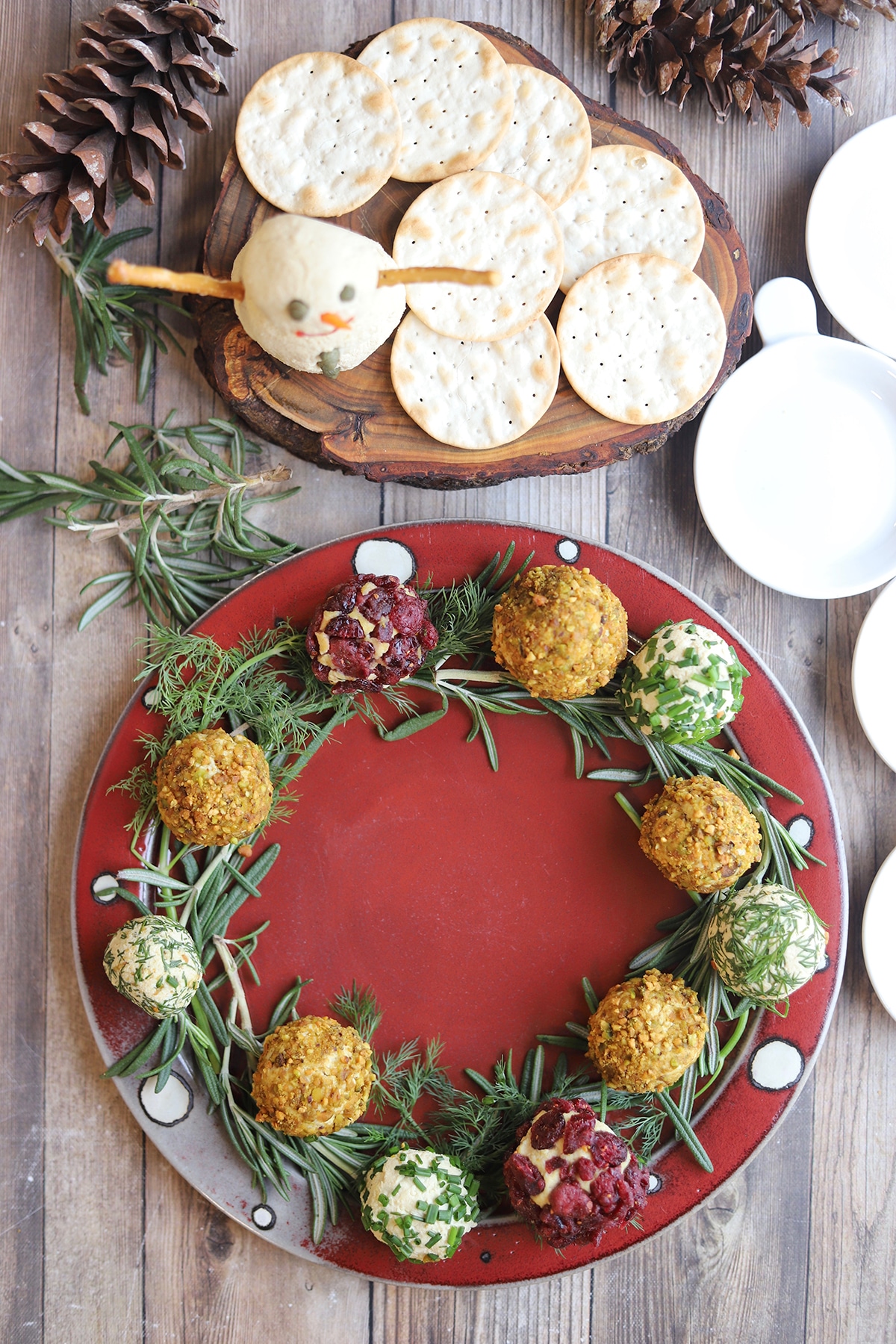 Overhead red platter with vegan cheeseballs wreath and tofu cheese snowman.