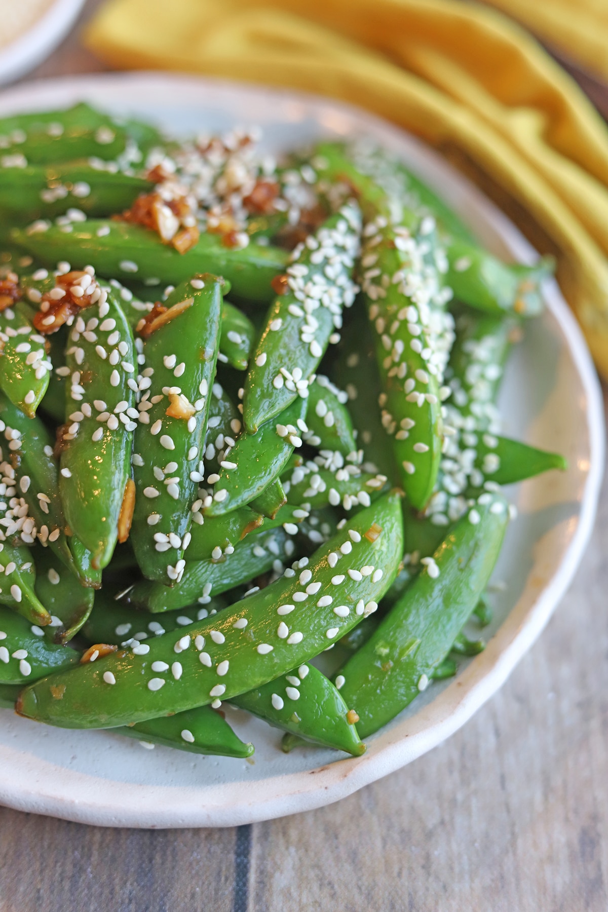Sugar snap peas on plate, topped with sesame seeds.