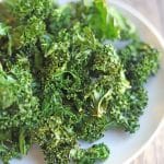 Text overlay: Crispy kale chips. Air fried or baked. Platter of kale chips on table.