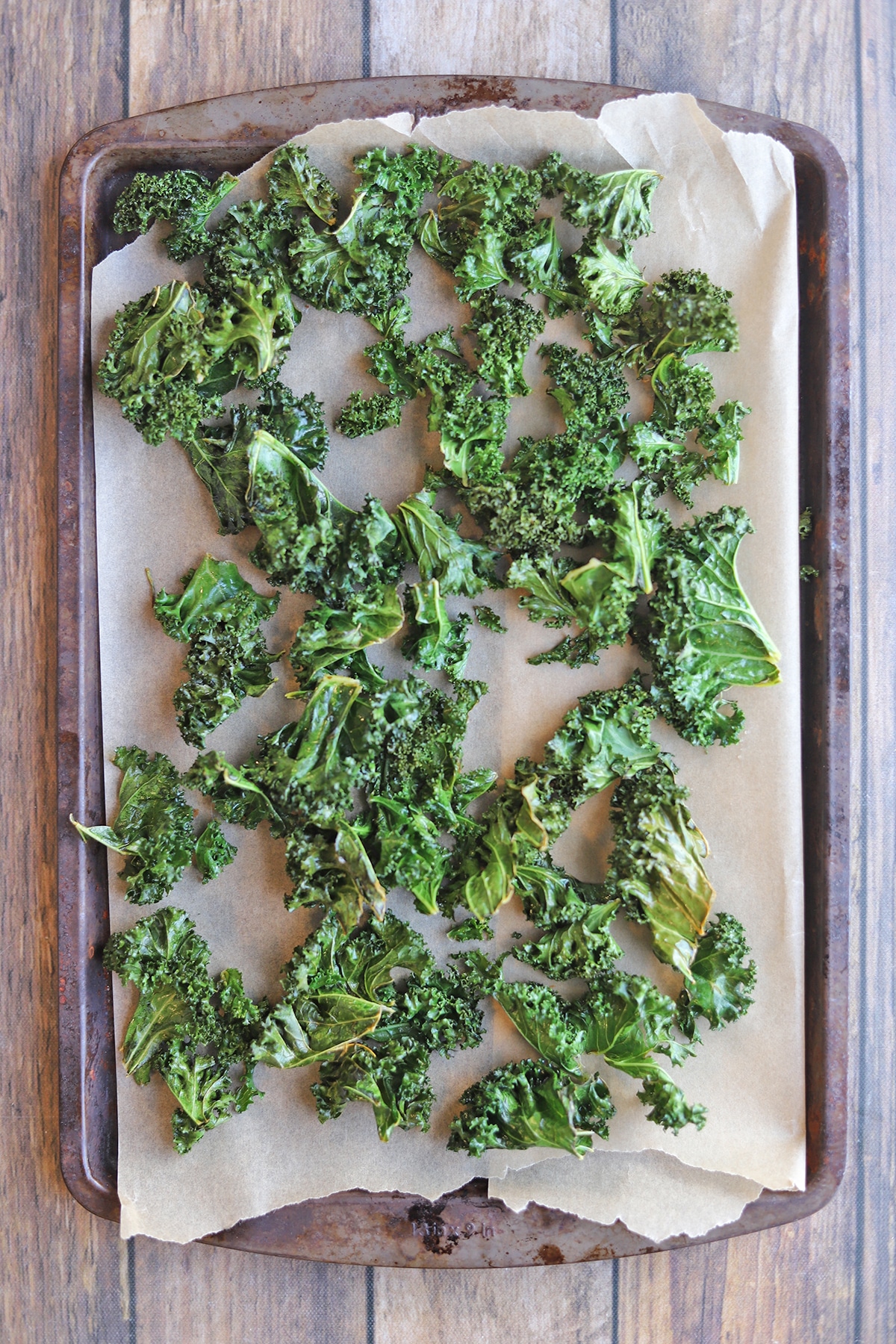 Kale chips on parchment paper covered baking sheet.