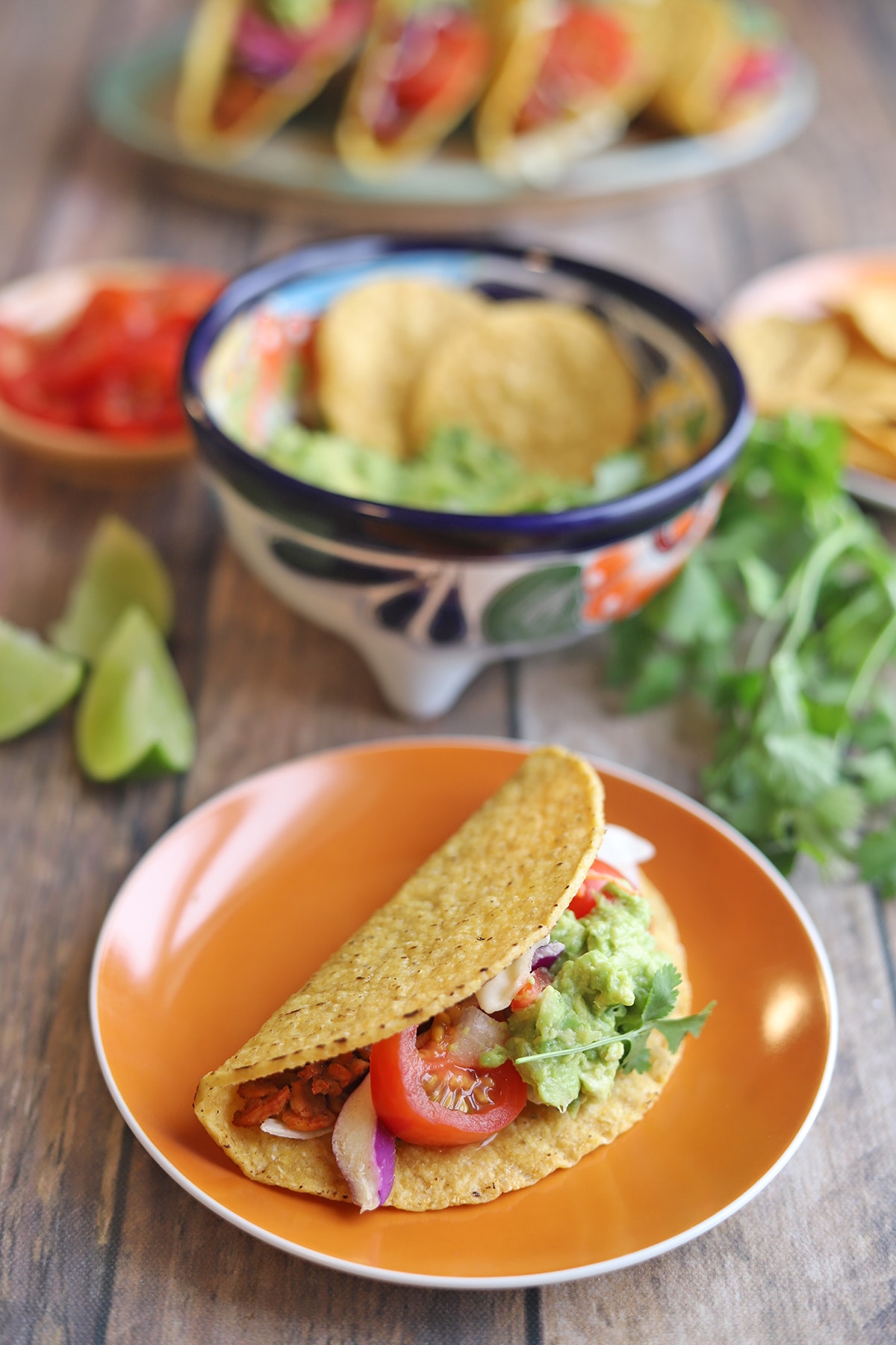 Orange plate holding single taco by bowl of guacamole.