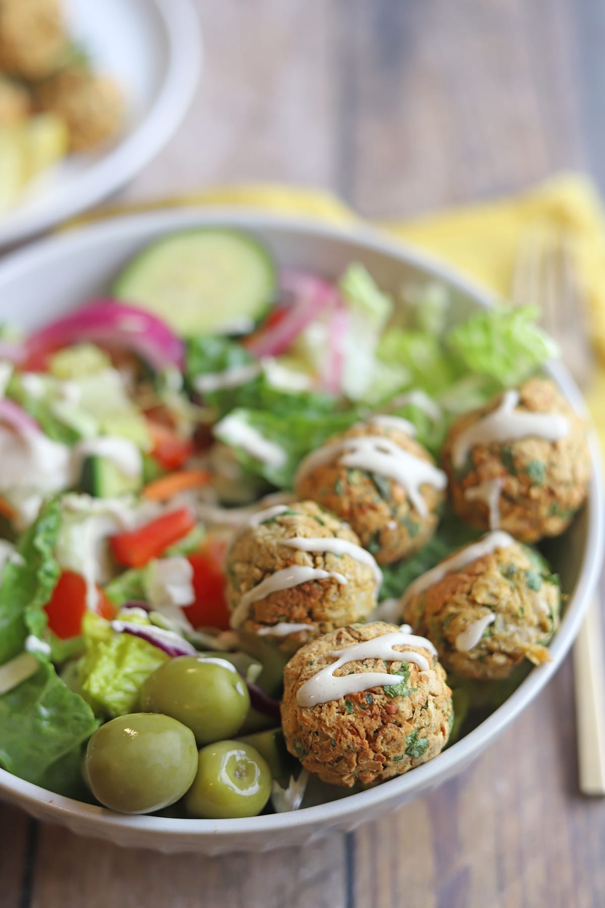 Falafel drizzled with tahini dressing on salad.